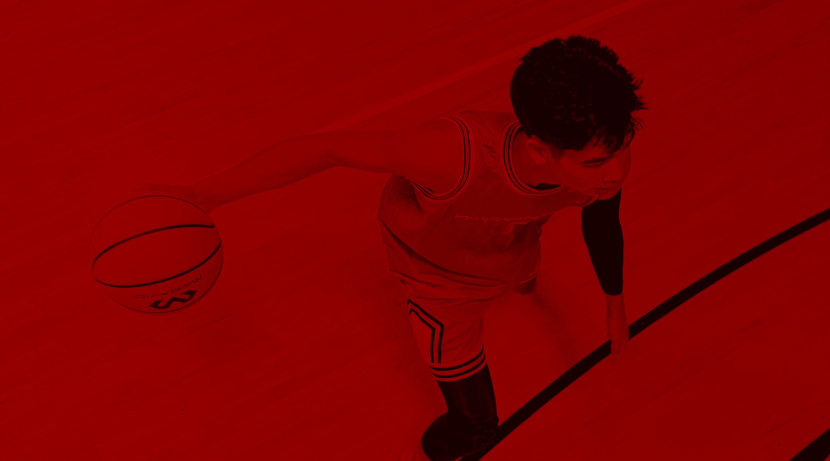 Person dribbling a basketball on a red court