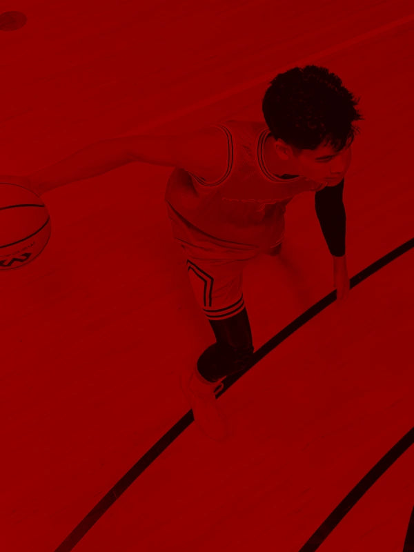 Person dribbling a basketball on a red court