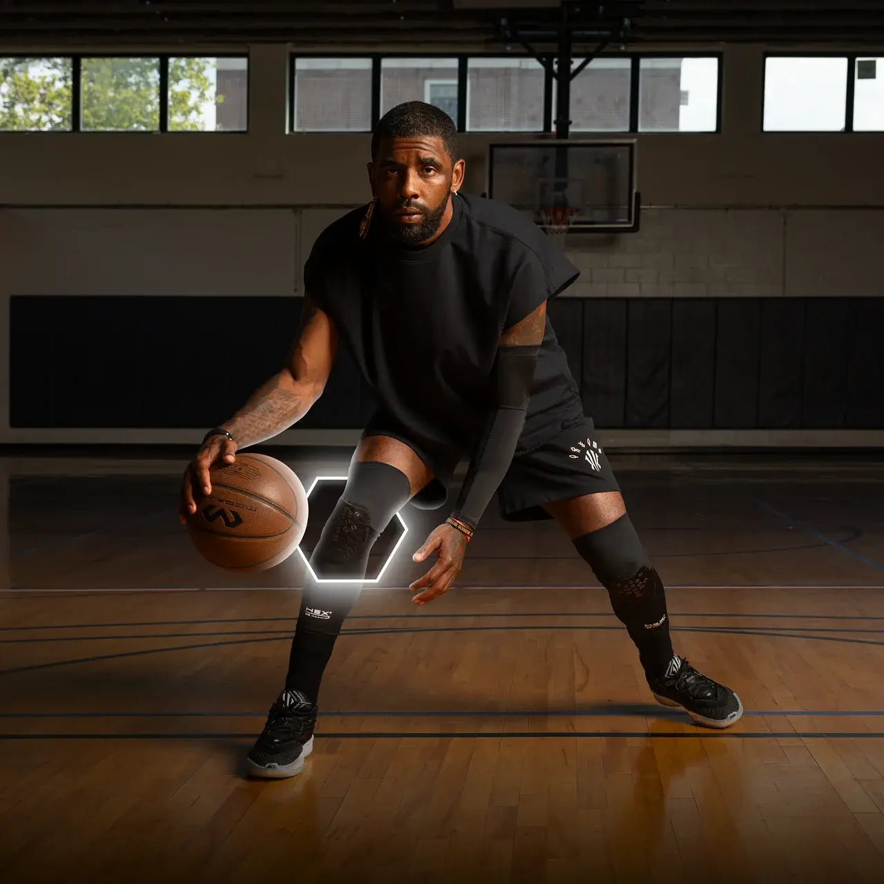 Kyrie Irving holding a basketball on a wooden court with a dark ambiance