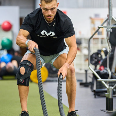 McDavid Phantom Knee Brace Lifestyle Image - Athlete Training With Battle Ropes in the Gym