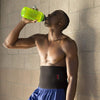 Lifestyle Image of Male Athlete Wearing McDavid Waist Trimmer While Sipping on Water Bottle